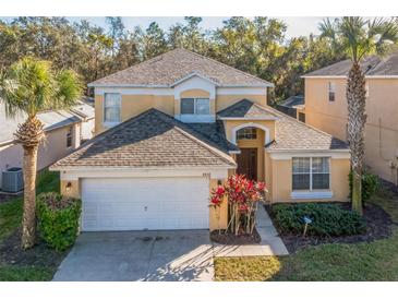 Two-story house with a tan exterior, white garage door, and landscaping at 8458 Secret Key Cove, Kissimmee, FL 34747