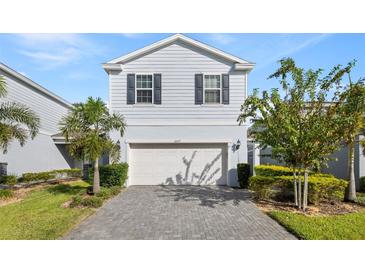 Two-story house with gray siding, white garage door, and landscaped front yard at 1627 Kona Ln, Davenport, FL 33897