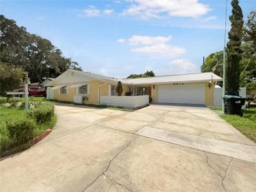 House exterior featuring a yellow single-story home with a two-car garage and a spacious driveway at 2214 Winnetka Ct, Orlando, FL 32818
