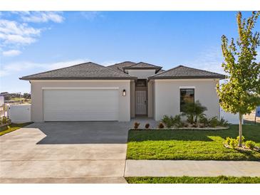 One-story home with attached garage, landscaping, and a neutral color palette at 6491 Octave St, Mascotte, FL 34753