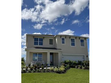 Two-story house with a landscaped lawn and a two-car garage at 3230 Belize Pl, Haines City, FL 33844