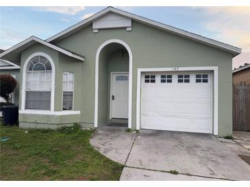 Light green house with white garage door and landscaping at 147 Dahlia Village Cir # Ge, Orlando, FL 32807