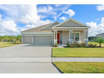 Single-story home with two-car garage, landscaped lawn, and inviting front porch at 6115 Claystone Way, Mount Dora, FL 32757