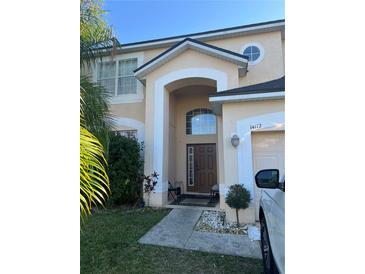 Two-story house with a tan exterior, a brown door, and landscaping at 14112 Morning Frost Dr, Orlando, FL 32828