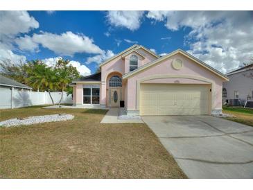 Two-story house with a pink exterior, two-car garage, and landscaped yard at 2908 Pembridge St, Kissimmee, FL 34747