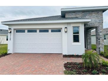 Modern one-story home with white garage door and paver driveway at 3168 Songbird Cir, Harmony, FL 34773