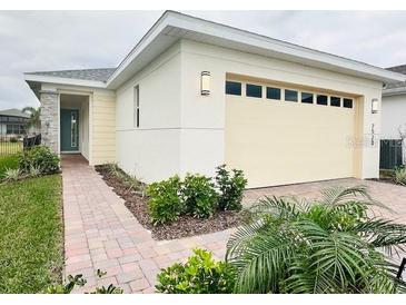 Two-car garage, light-colored exterior, and landscaped walkway at 7520 Castlewood Ct, Harmony, FL 34773