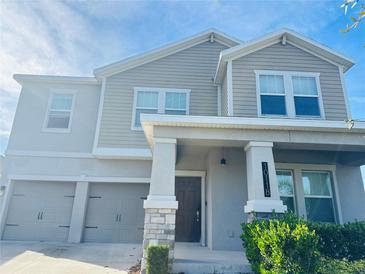 Two-story house with gray siding, stone accents, and a two-car garage at 10118 Storey Grove Way, Winter Garden, FL 34787