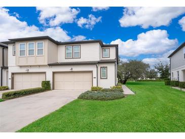 Two-story townhome with two-car garage, landscaped lawn, and charming exterior at 664 Benoi Dr, Davenport, FL 33896