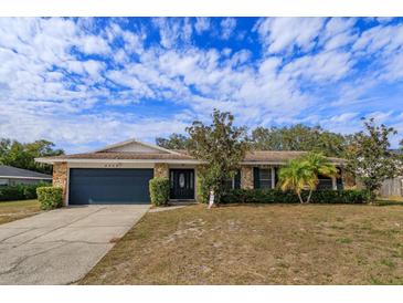 Single-story home with stone facade, dark gray garage door, and mature landscaping at 6928 Sugarbush Dr, Orlando, FL 32819