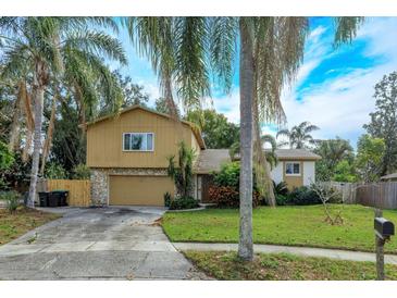 Tan two-story house with a large yard, driveway, and palm trees at 8510 Cedar Cove Ct, Orlando, FL 32819