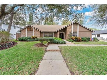 Brick ranch home with mature landscaping and a paved walkway at 1103 Superior Ct, Winter Springs, FL 32708