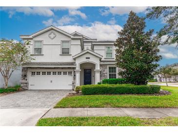 Two-story house with white and stone exterior, three-car garage, and landscaped lawn at 1550 Observer Ln, Davenport, FL 33896