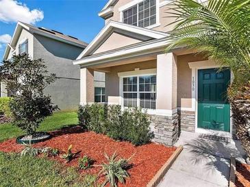 Two-story house with a green door and stone accents, landscaped yard with red mulch at 1030 Bending Oak Trl, Winter Garden, FL 34787