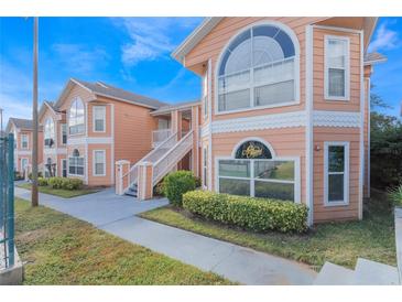 Exterior view of a two-story peach-colored building with stairs and walkway at 8709 Rockingham Ter # A, Kissimmee, FL 34747