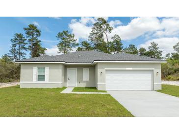 One-story home with gray shingle roof, white garage door, and landscaped lawn at 17406 Sw 38Th Avenue Rd, Ocala, FL 34473