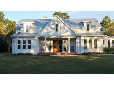 White farmhouse with metal roof, front porch, and landscaping at 2293 Eldorado Ct, Saint Cloud, FL 34771