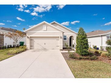 Tan house with a two-car garage and landscaped front yard at 7836 June Ln, Wildwood, FL 34785