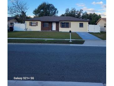 One-story house with a brown brick facade, white fences, and a well-maintained lawn at 4523 Ligustrum Way, Orlando, FL 32839