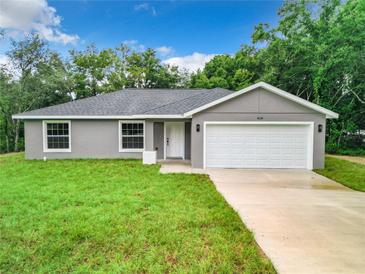 Newly constructed home with gray siding, white garage door, and a well-manicured lawn at 22474 Sw Rainbow Lakes Blvd, Dunnellon, FL 34431