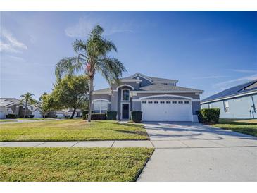 Two-story house with gray siding, white garage door, and palm tree in front at 2214 Wyndham Palms Way, Kissimmee, FL 34747