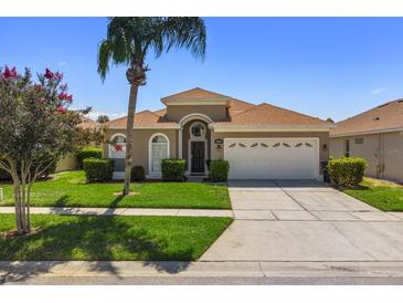 Tan one-story house with a two-car garage and landscaped lawn at 8144 Sun Palm Dr, Kissimmee, FL 34747