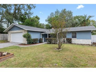 Ranch-style home with light blue exterior, white garage door, and well-maintained lawn at 1709 Ne 28Th Pl, Ocala, FL 34470