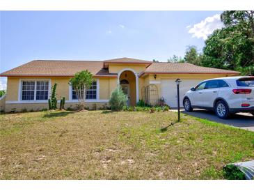 Single-story house with a yellow exterior, a car in the driveway, and a well-maintained lawn at 567 Silver Course Run, Ocala, FL 34472