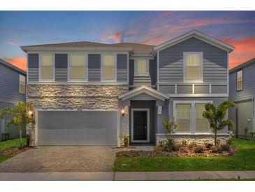 Two-story home with gray siding, stone accents, and a two-car garage at 3004 Mahalo Dr, Davenport, FL 33897