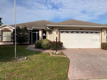 House exterior featuring a two-car garage and landscaped lawn at 610 Grand Vista Trl, Leesburg, FL 34748