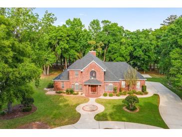 Brick house with large yard and driveway, surrounded by trees at 7086 Se 12Th Cir, Ocala, FL 34480