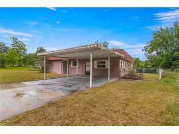 Pink single story home with carport and fenced yard at 46 Lake Court Loop, Ocala, FL 34472