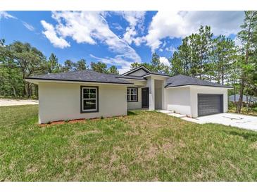 One-story home with gray garage and white exterior at 13359 Sw 80Th St, Dunnellon, FL 34432