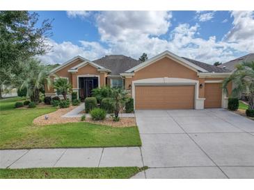Tan two-story house with three car garage and landscaping at 9818 Sw 63Rd Loop, Ocala, FL 34481