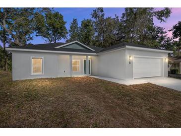 Two-bedroom home with a two-car garage and landscaping at 5 Emerald Trl, Ocala, FL 34472