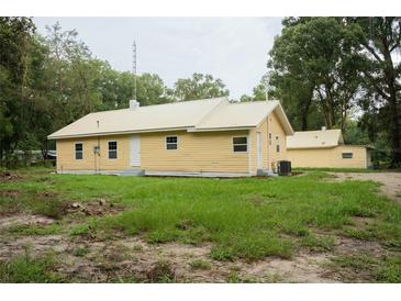 Yellow house with metal roof and detached garage at 1750 Ne 180Th St, Citra, FL 32113