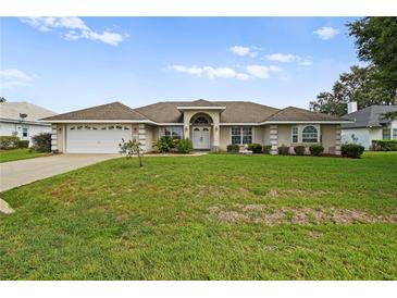 Single-story home with a two-car garage and well-maintained lawn at 5851 Sw 86Th Pl, Ocala, FL 34476