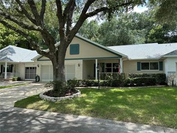 Front view of a light beige house with a covered porch and well-maintained landscaping at 8420 Sw 92Nd St # B, Ocala, FL 34481
