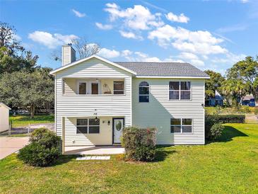 Two-story house with light yellow siding, gray roof, and a well-manicured lawn at 10 Se Chinica Drive, Summerfield, FL 34491