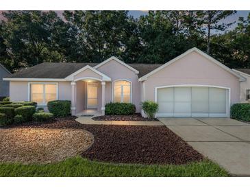 Pink house with two car garage and mature landscaping at dusk at 11696 Sw 71St Cir, Ocala, FL 34476