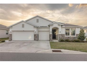Two-story house with a three-car garage, stone accents, and a beautifully landscaped yard at 8314 Sw 59Th Ter, Ocala, FL 34476