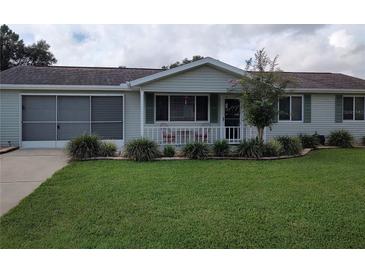 Ranch-style home with carport, mature landscaping, and lawn at 8750 Sw 116Th Place Rd, Ocala, FL 34481