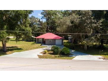 Single story home with red metal roof, gray siding, and a two-car garage at 1331 Se 169Th Terrace Rd, Silver Springs, FL 34488