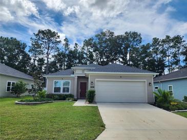 Tan house with two car garage and well-manicured lawn at 7867 Sw 74Th Loop, Ocala, FL 34481