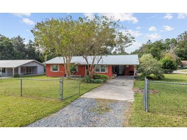 Red house with metal roof, driveway, and fenced yard at 2810 Se 8Th St, Ocala, FL 34471