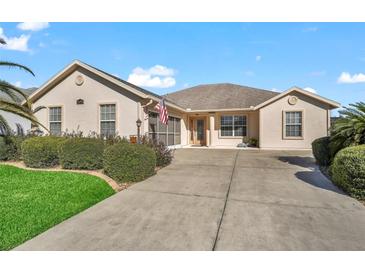 Tan one-story house with a two-car garage and landscaped front yard at 16895 Se 110Th Court Rd, Summerfield, FL 34491