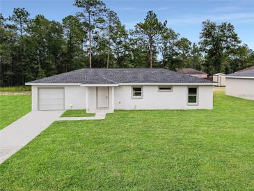 Newly constructed home with a white exterior, grassy lawn, and attached garage at 2680 Sw 150Th Ct, Ocala, FL 34481