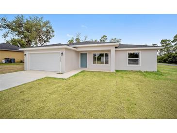 Newly constructed home with a white exterior, grassy lawn, and attached garage at 175 Fisher Way Trl, Ocklawaha, FL 32179