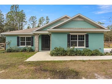 Newly constructed home with light teal exterior, black shutters, and stone accents at 6138 Sw 121St Ter, Ocala, FL 34481