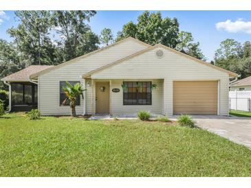 One-story house with beige siding, attached garage, and a well-maintained lawn at 21174 Sw Peach Blossom St, Dunnellon, FL 34431